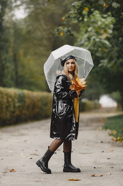 Foto gratuita la ragazza cammina. donna in un cappotto nero. bionda con un berretto nero. signora con l'ombrello.