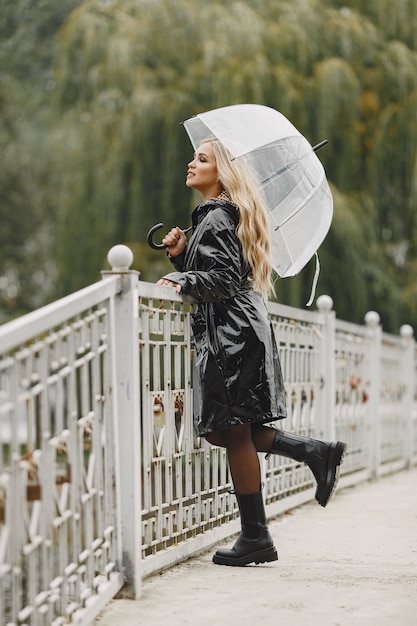 girl walks. woman in a black coat. blonde with a umbrella.