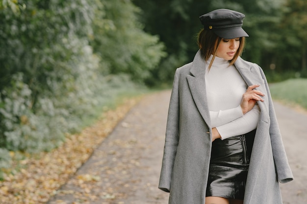 La ragazza cammina. donna in un cappotto grigio. bruna con un berretto nero.