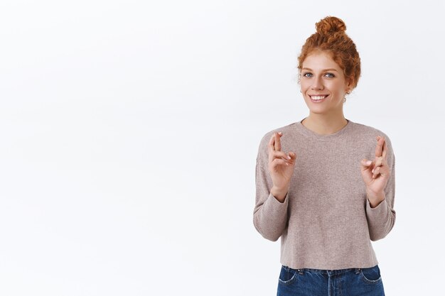 Girl want something happen so start pray. Cheerful, hopeful and optimistic redhead woman with curly hair, cross fingers good luck, smiling, anticipating good news, believe dreams come true