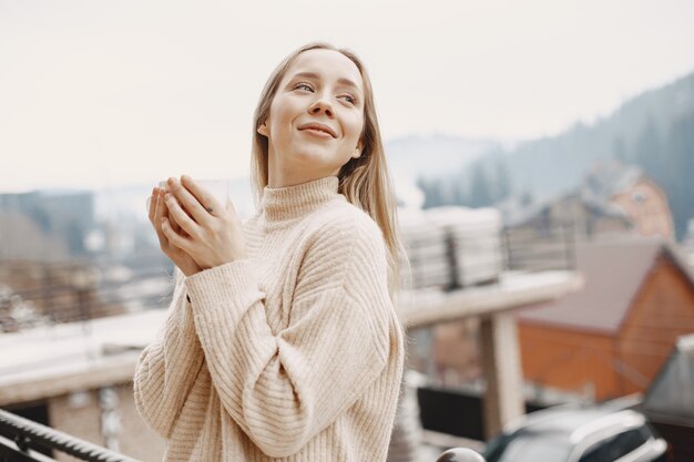 Girl in a warm light coat. Vacation in mountains. Lady with long hair.