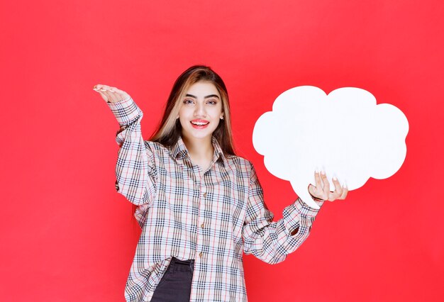Girl in warm sweater holding a cloud shape ideaboard and nominating the person ahead