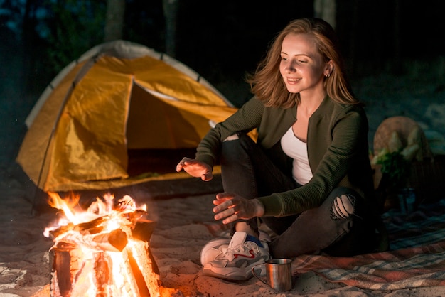 Girl warming up by a campfire 