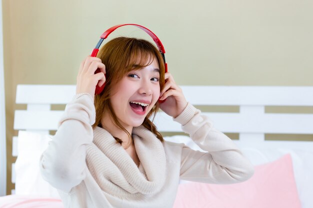 The girl was wearing headphones nd enjoying music on the bed