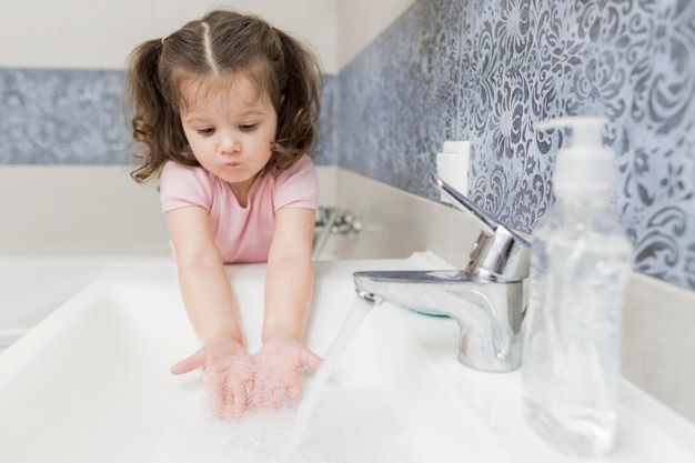 Girl washing hands in sink