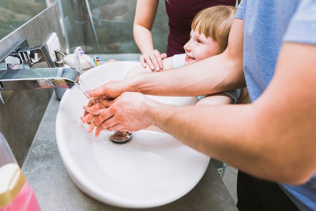 Girl washing hands with parents