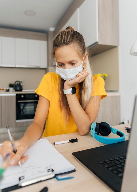 Girl wearing face mask doing her homework