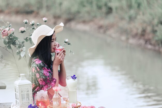 ウォーターフロントに座って花のドレスを着ている少女