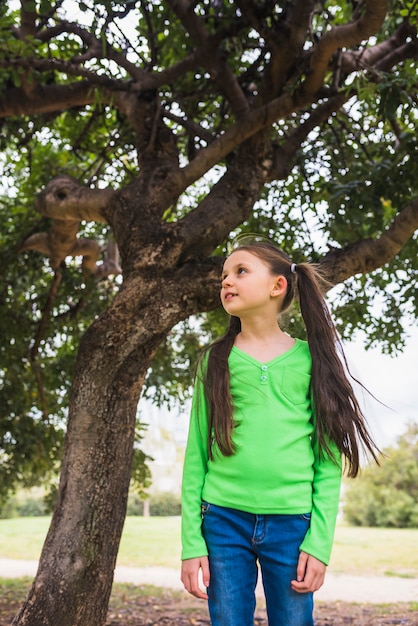 Girl wearing green t-shirt standing under big tree