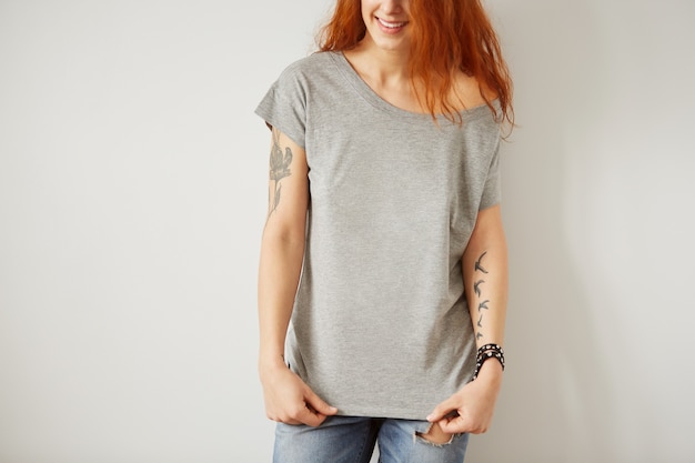 Girl wearing grey blank t-shirt standing on white wall