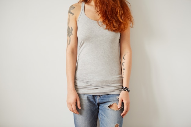 Foto gratuita ragazza che indossa la maglietta in bianco grigia in piedi sul muro bianco