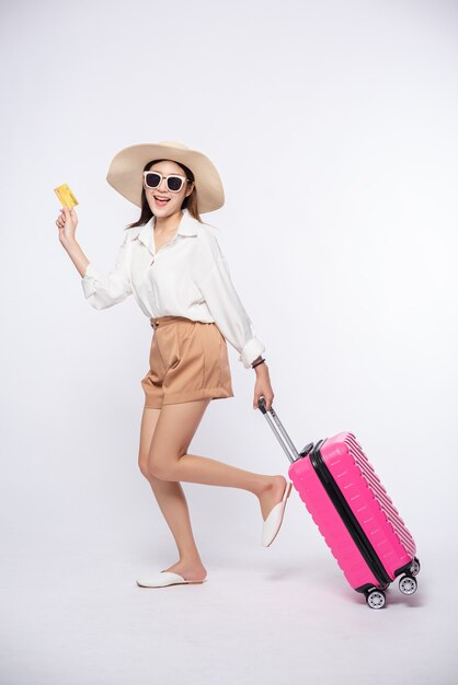 旅行にクレジットカードとスーツケースを持っている帽子をかぶっている女の子