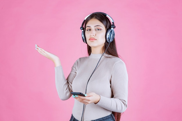 Free photo girl wearing headphones and pointing to somewhere