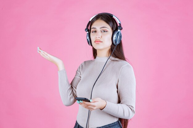 Girl wearing headphones and pointing to somewhere