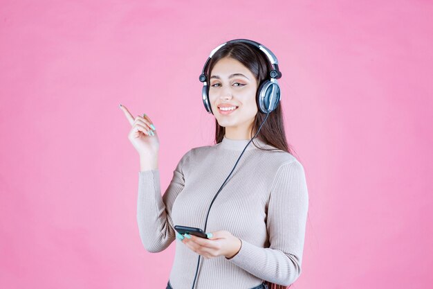 Girl wearing headphones and pointing to somewhere