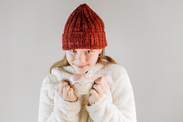 Ragazza che indossa cappello a maglia tenendo la tazza di caffè