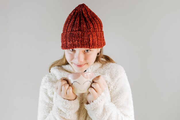 Girl wearing knit hat holding cup of coffee