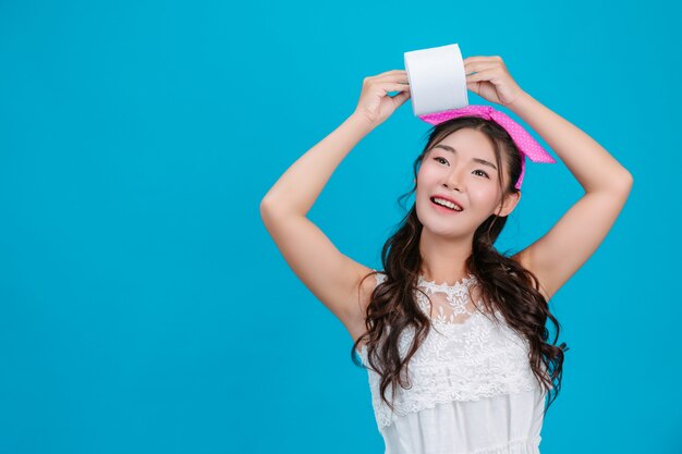 Girl wearing white pajamas Holding a rolltissue paper in the hand on the blue .