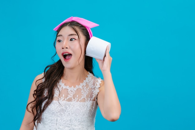 Girl wearing white pajamas holding a rolltissue paper in the hand on the blue