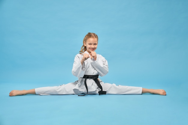 Girl in white kimono with black belt in combat position.