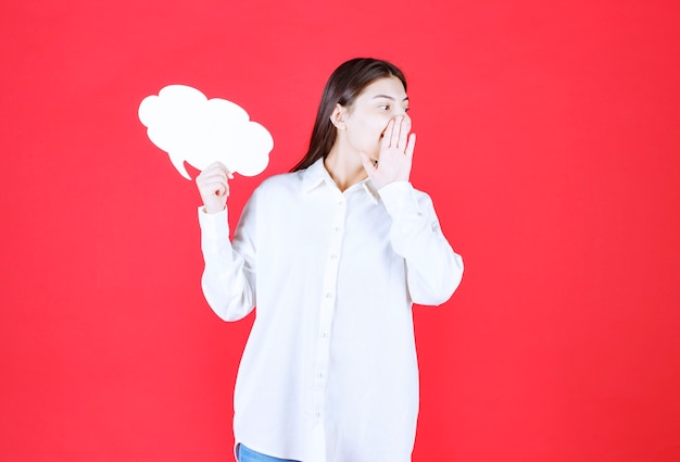 Girl in white shirt holding a cloud shape info board and calling someone