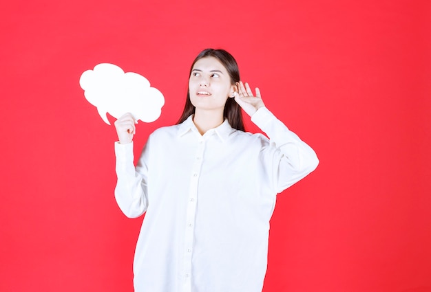 Girl in white shirt holding a cloud shape info board and looks confused and thoughtful