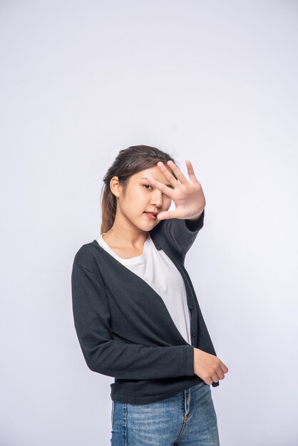 Girl in white stretch jeans and do hand prohibition sign on white wall.