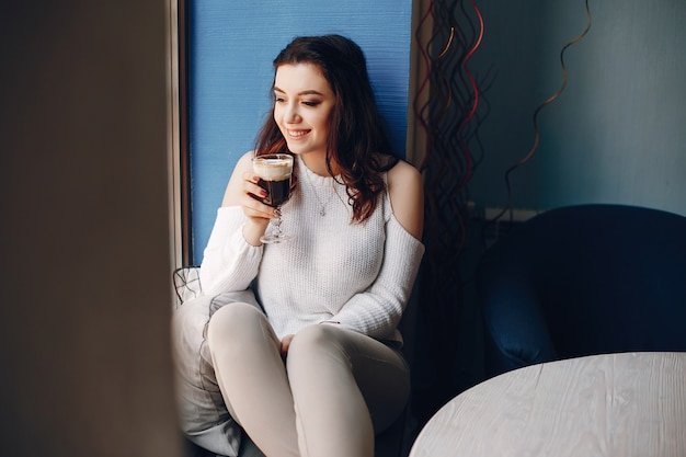 Girl in a white sweater sitting alone in cafe