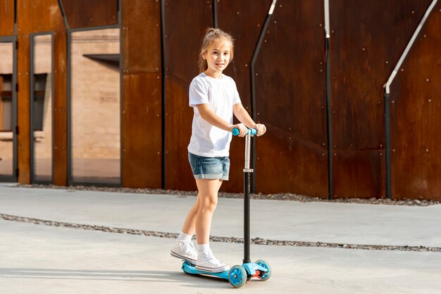 Girl in white t-shirt riding blue scooter