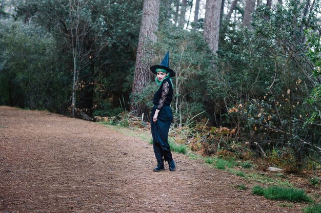 Girl in witch hat standing on path