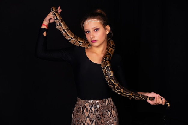 黒​の​背景​に​彼女​の​体​に​ヘビ​を​持つ​少女