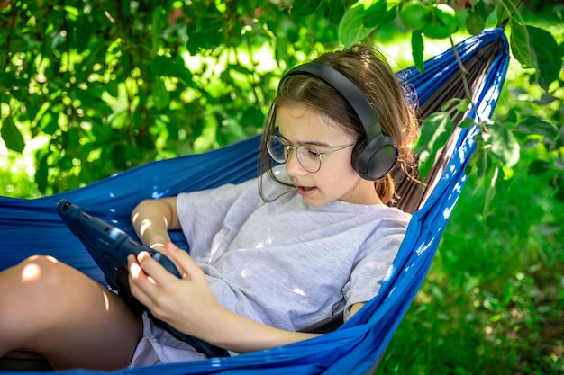 Бесплатное фото Девушка с планшетом в гамаке в саду