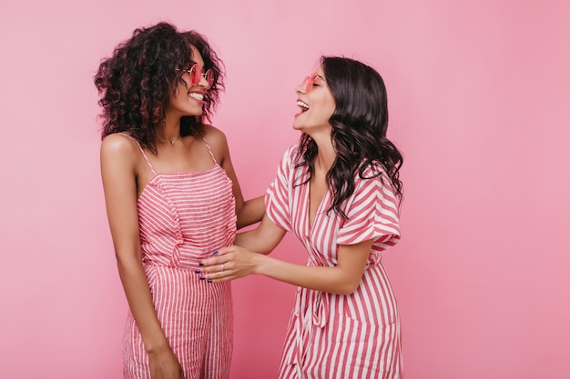 Free photo girl with amazing smile tells her friend funny story. indoors portrait of models with tanned skin.