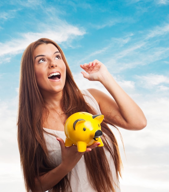 Free photo girl with arm up holding moneybox