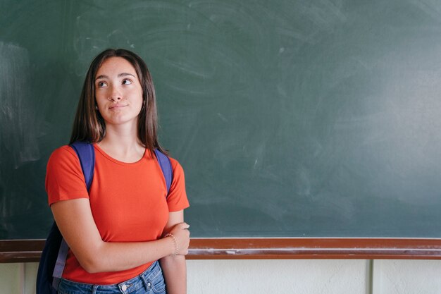Girl with backpack in front of the blackboard