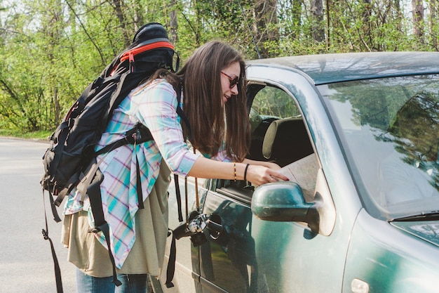 Girl with backpack talking to a driver