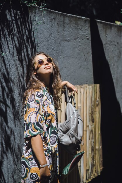 girl with a backpack, wearing sunglasses, in a tropical garden