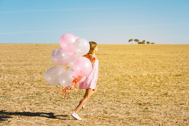 Foto gratuita ragazza con palloncini in esecuzione in campo