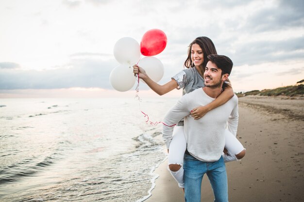 Girl with balloons while her boyfriend carries her on her back