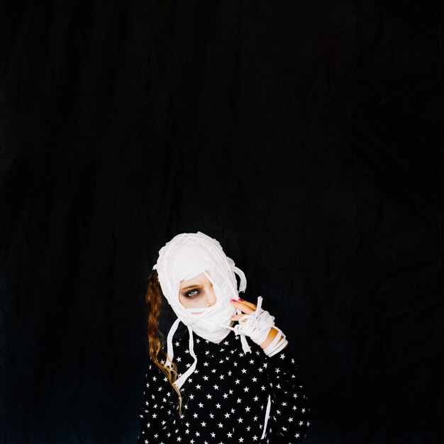 Girl with bandages isolated in black room