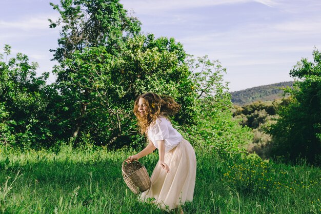 Girl with basket walking in field