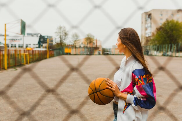 Free photo girl with basketball behind fence