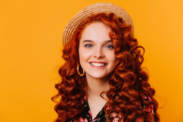 Girl with beautiful blue eyes and lush eyelashes genuinely smiles. Closeup portrait of ginger lady in boater on isolated space.