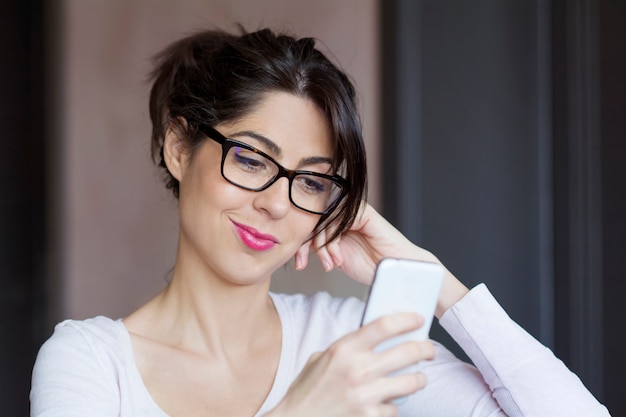 Girl with black glasses checking her smartphone