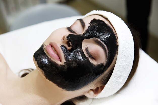 Girl with black mask lies on the table  in spa saloon