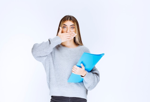 Free photo girl with a blue folder looks confused and terrified.