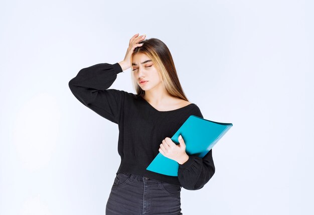 Girl with a blue folder looks confused and thoughtful. High quality photo