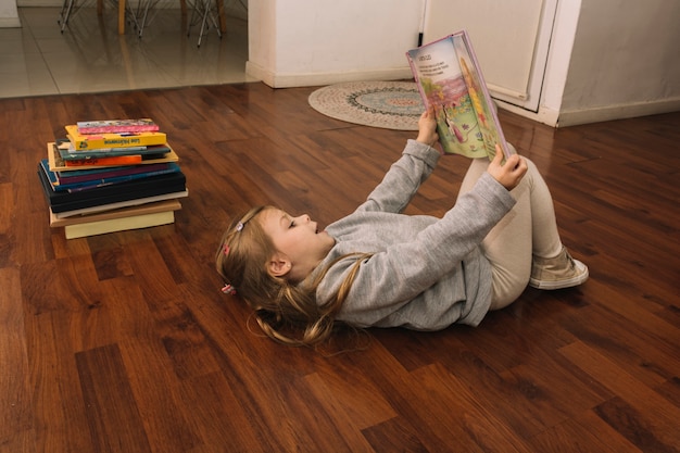 Foto gratuita ragazza con il libro sdraiato sul pavimento