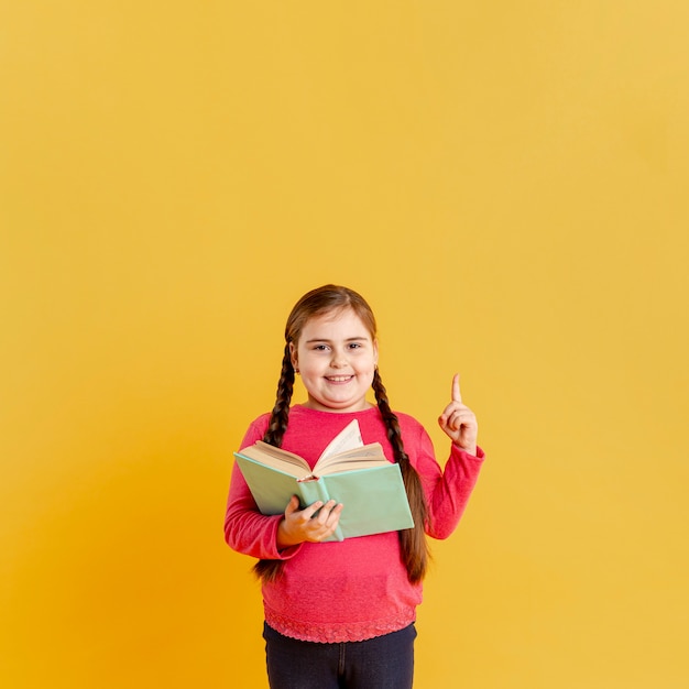 Free photo girl with book pointing above