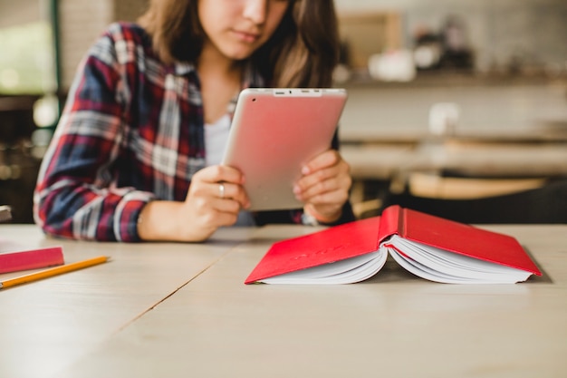 Free photo girl with book and tablet at table